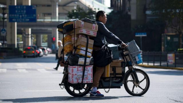 A delivery man on an electric bike crosses a street as he delivers parcels during the 'Double Eleven' Online Shopping Festival day in Shanghai on November 11, 2016.